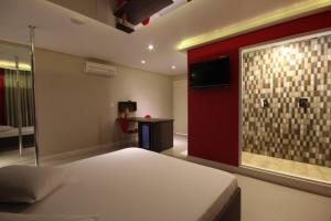 a bedroom with a bed and a wall with a tv at Flow Motel (Adult Only) in Valinhos
