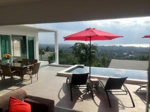 eine Terrasse mit einem Tisch, Stühlen und einem Sonnenschirm in der Unterkunft Pearl Villa in Nathon