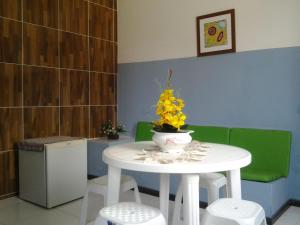 uma mesa branca com um vaso de flores amarelas em Pousada Odemir Ferreira em Vera Cruz de Itaparica