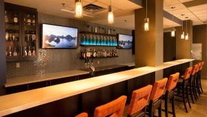 a bar in a restaurant with orange chairs at Holiday Inn & Suites Mississauga West - Meadowvale by IHG in Mississauga