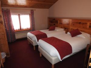 1 dormitorio con 2 camas y ventana en Hotel Le Clocher, en Champoluc