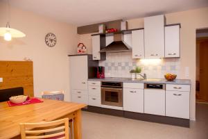 kuchnia z białymi szafkami i drewnianym stołem w obiekcie Apartment Erler w mieście Hippach +16 zdjęć