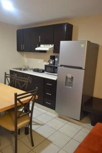 a kitchen with a stainless steel refrigerator and a table at Los Jitos Hotel & Suites in San Carlos