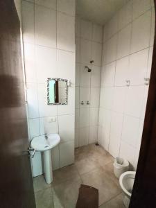 een badkamer met een wastafel, een spiegel en een toilet bij Hotel Goll in Limeira