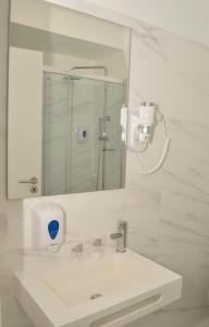 W białej łazience znajduje się umywalka i lustro. w obiekcie THE FOZ Beach Hotel w mieście Figueira da Foz