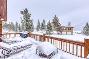 um deque coberto de neve com duas cadeiras e uma casa em Grand Lake Grandeur em Grand Lake