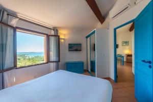a bedroom with a bed and a large window at Résidence Belvedere de Palombaggia in Porto-Vecchio