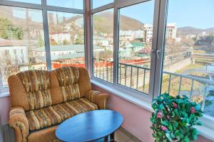 a room with a chair and a table and windows at Гостевой дом "Одиссея" in Tuapse