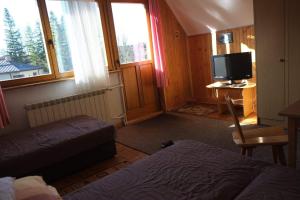 Pokój z 2 łóżkami, telewizorem i biurkiem w obiekcie Pokoje u Tadeusza w Zakopanem