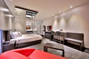 a bedroom with a bed and a desk and a kitchen at Hôtel Ô Laval in Laval