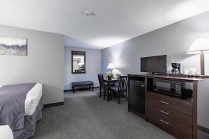 ein Hotelzimmer mit einem Bett und einem Schreibtisch mit einer Mikrowelle in der Unterkunft Mt. Madison Inn & Suites in Gorham