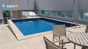 a swimming pool with chairs and a table and a table and chairs at Apto. 1 dormitório no M. de Nassau - Ed. Manhattan Home Service 302 in Caruaru