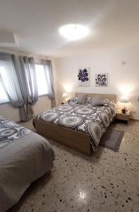 a bedroom with a large bed and two windows at Le Casette di Nonna Rosa in Fontanarossa Catania Airport in Catania