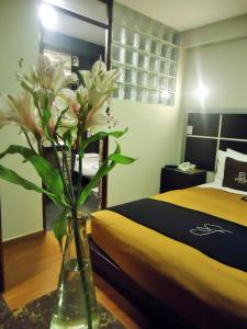 a vase with flowers on a table next to a bed at Hotel San Francisco Plaza in Cusco