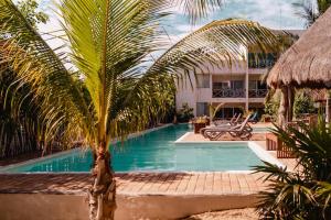 a swimming pool with a palm tree in front of a building at Luxury Condo, the hidden gem Playa Chacá. Live it! in Progreso