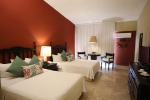 a hotel room with two beds and a table at Hotel Montetaxco in Taxco de Alarcón