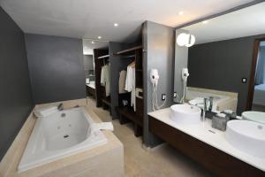a bathroom with a tub, sink and mirror at Hotel Montetaxco in Taxco de Alarcón