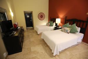 a hotel room with two beds and a television at Hotel Montetaxco in Taxco de Alarcón