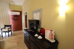 a hotel room with a television and a dresser in a room at Hotel Montetaxco in Taxco de Alarcón