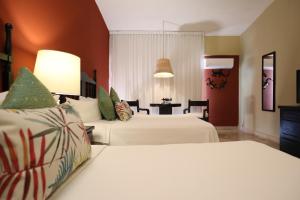 a hotel room with two beds and a table at Hotel Montetaxco in Taxco de Alarcón