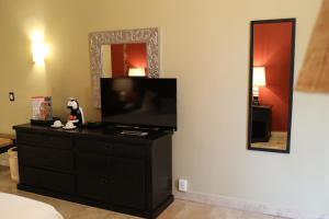 a room with a television on a dresser with a mirror at Hotel Montetaxco in Taxco de Alarcón
