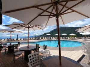 a pool with tables and chairs and umbrellas at Hotel Montetaxco in Taxco de Alarcón
