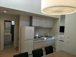 uma cozinha com um frigorífico branco, uma mesa e cadeiras em The Seasons Apartments Hakuba em Hakuba