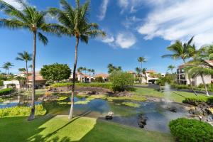 Blick auf ein Resort mit Palmen und einem Teich in der Unterkunft Shores at Waikoloa #105 in Waikoloa