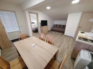 cocina y sala de estar con mesa de madera y sillas en S&M Apartmani, en Soko Banja