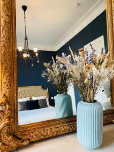 dos jarrones azules con flores delante de un espejo en Romance au coeur de Bordeaux / Jardin Public, en Burdeos