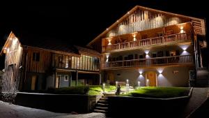a large wooden building with a balcony at night at Chalet 1703 - Alpine Lodge & Spa - Adults Only in Le Petit-Bornand-lès-Glières