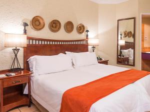 um quarto com uma grande cama branca e um espelho em aha Kopanong Hotel & Conference Centre em Bredell