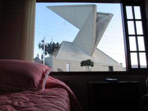 1 dormitorio con vistas a una iglesia a través de una ventana en Hotel El Cangrejo, en Paipa