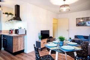 a kitchen and a living room with a table and chairs at Chic & Cosy Appartement avec Terrasse, Parking Privatif in Saint-Grégoire
