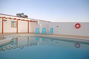 einem Pool mit zwei blauen Stühlen und einem Gebäude in der Unterkunft Monte da Moloneta in Trindade