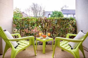 two green chairs and a table on a patio at Chic & Cosy Appartement avec Terrasse, Parking Privatif in Saint-Grégoire