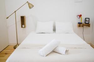 a white bed with white sheets and a lamp at Cosy and Modern Flat in Porto in Porto
