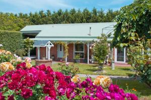 a house with a bunch of flowers in front of it at Lakeside Cottage Luxury B&B in Mount Dandenong