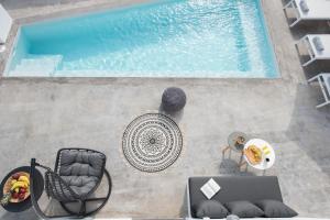 Vóthon的住宿－White Orchid Suites，享有带椅子和桌子的游泳池的上方景色