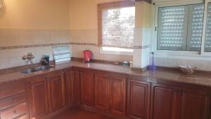 een keuken met houten kasten, een wastafel en een raam bij Chalets La Lucinda in Cortaderas