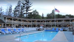 un complejo con piscina, sillas y bandera americana en Mt. Madison Inn & Suites en Gorham