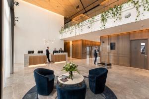 um lobby com uma mesa e cadeiras e pessoas em Novotel Christchurch Airport em Christchurch