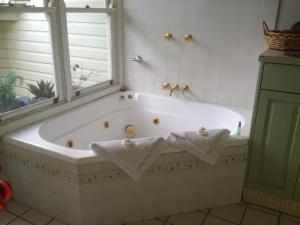 a white bath tub sitting next to a white sink at Casablanca Enchanted Cottage in Nelson Bay