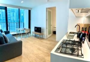墨爾本的住宿－ReadySet Apartments at Lighthouse，厨房以及带炉灶和沙发的客厅。