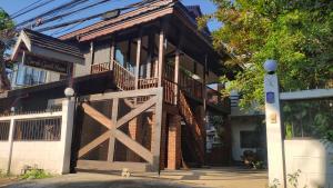 ein Haus mit einem Holztor und einem Balkon in der Unterkunft Sarah Guest House in Chiang Mai