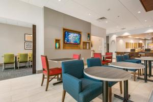 Una sala de espera con mesas y sillas y un televisor. en Holiday Inn Express & Suites - Carrollton West by IHG, en Carrollton