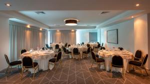 a banquet room with tables and chairs with white tablecloths at Holiday Inn & Suites - Merida La Isla by IHG in Mérida