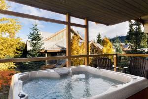 a jacuzzi tub on a patio with a view of a house at Glaciers Reach by Allseason Vacation Rentals in Whistler