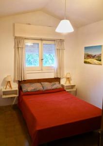 1 Schlafzimmer mit einem roten Bett und 2 Fenstern in der Unterkunft Casa en Villa Amancay in Amboy
