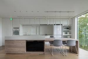 a kitchen with white cabinets and a table and chairs at Yama no Oto in Furano